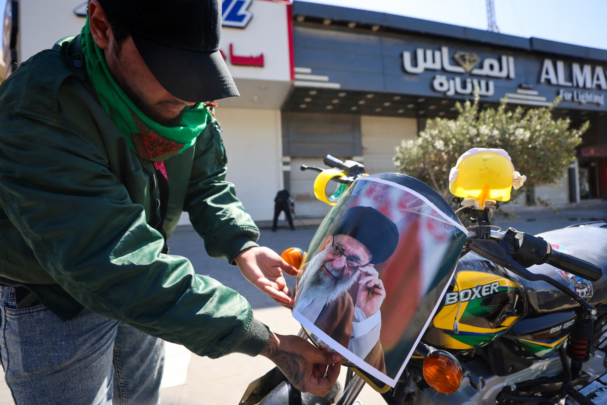 رجل عراقي يلصق صورة خامنئي على دراجته النارية في بغداد، غداة مقتله بضربات أميركية-إسرائيلية. (أ ف ب)