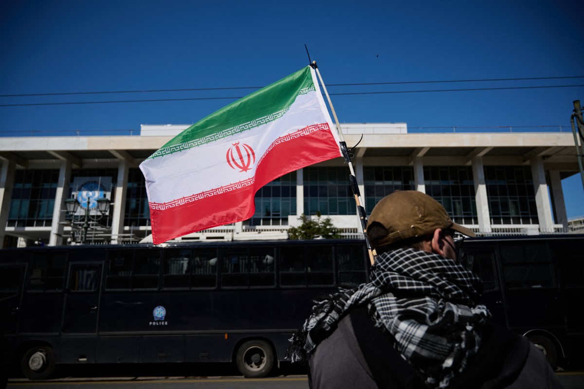 متظاهر يحمل العلم الإيراني خلال احتجاج ضد الهجوم الأميركي-الإسرائيلي في أثينا. (أ ف ب)