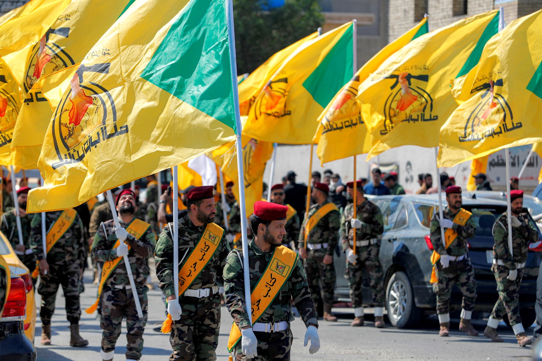 عناصر من كتائب حزب الله يحملون رايات التنظيم، في جنازة لمقاتلين قُتلوا في غارة جوية أميركية إسرائيلية على مقرهم في القائم. (أ ف ب)