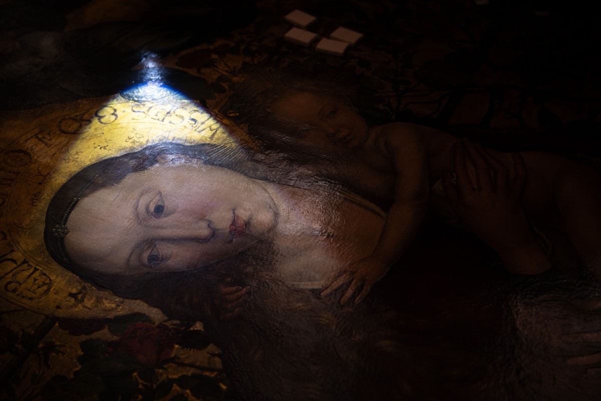 تشير المرممة جولي سوتر إلى أماكن تقشّرت فيها طبقة الطلاء. (أ ف ب)