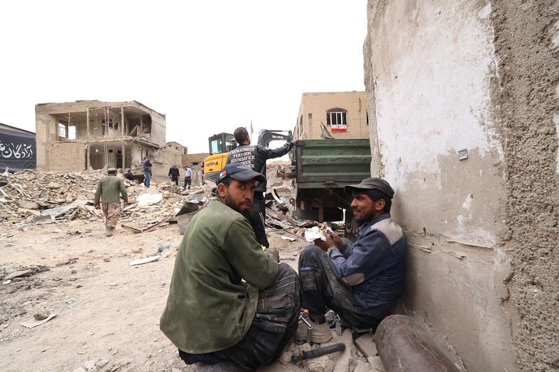 رجال إيرانيون يستريحون أثناء إزالة الأنقاض من حي سكني متضرر في أعقاب غارة عسكرية على طهران، (ا ف ب).