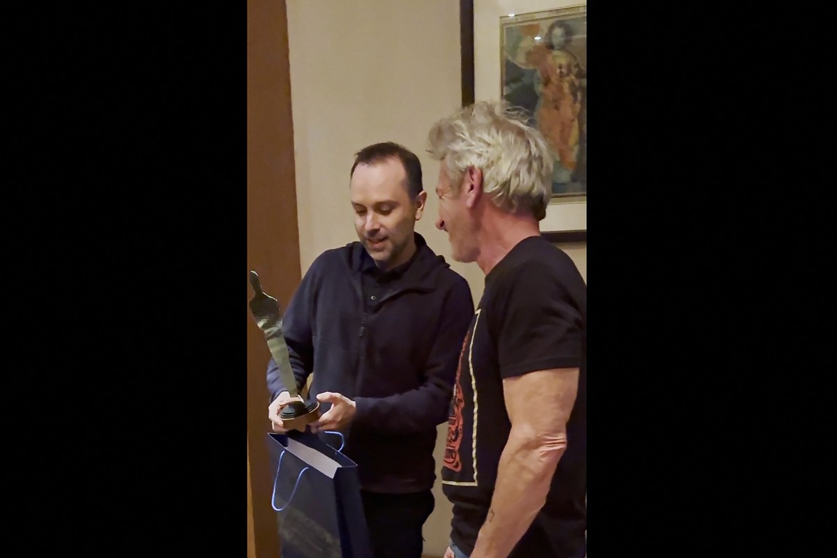 شون بن متسلّماً تمثالاً رمزياً نُحت من حطام عربة قطار. (17 آذار/مارس 2026 - أ ف ب)