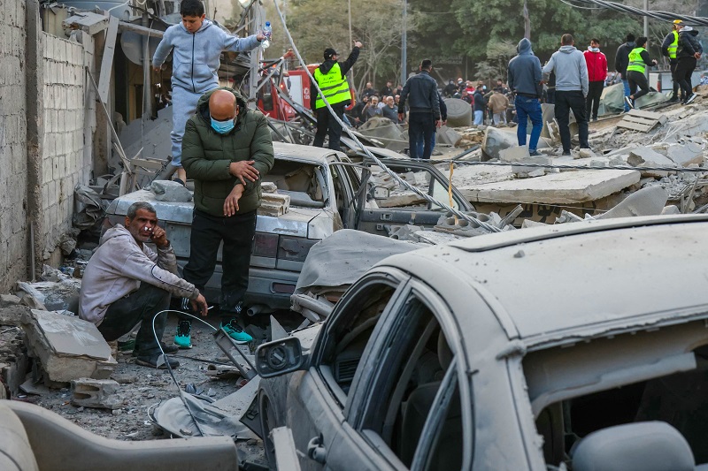 لبنانيون في موقع غارة جوية إسرائيلية في حي الباشورة في بيروت، (ا ف ب).