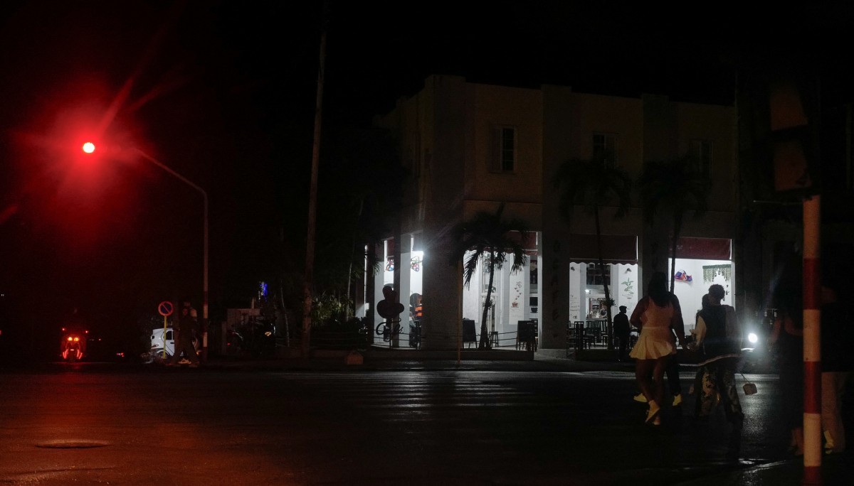 يتجمع الناس بجوار شركة خاصة مزودة بمولد كهربائي خلال انقطاع التيار الكهربائي على مستوى البلاد في هافانا. (أ ف ب)