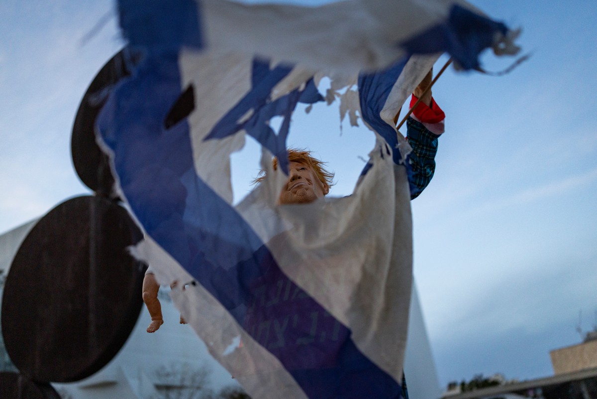 متظاهر يحمل علماً إسرائيلياً ممزقاً، خلال الاحتجاج الأسبوعي المناهض للحرب في ساحة هابيما في تل أبيب. (أ ف ب)