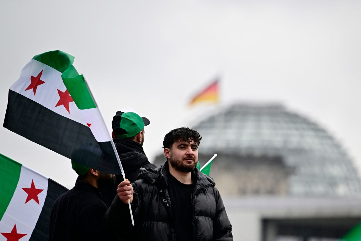 سوريون يتجمعون أمام مبنى الرايخستاغ في برلين قبيل اجتماع ميرتس والشرع. (أ ف ب)