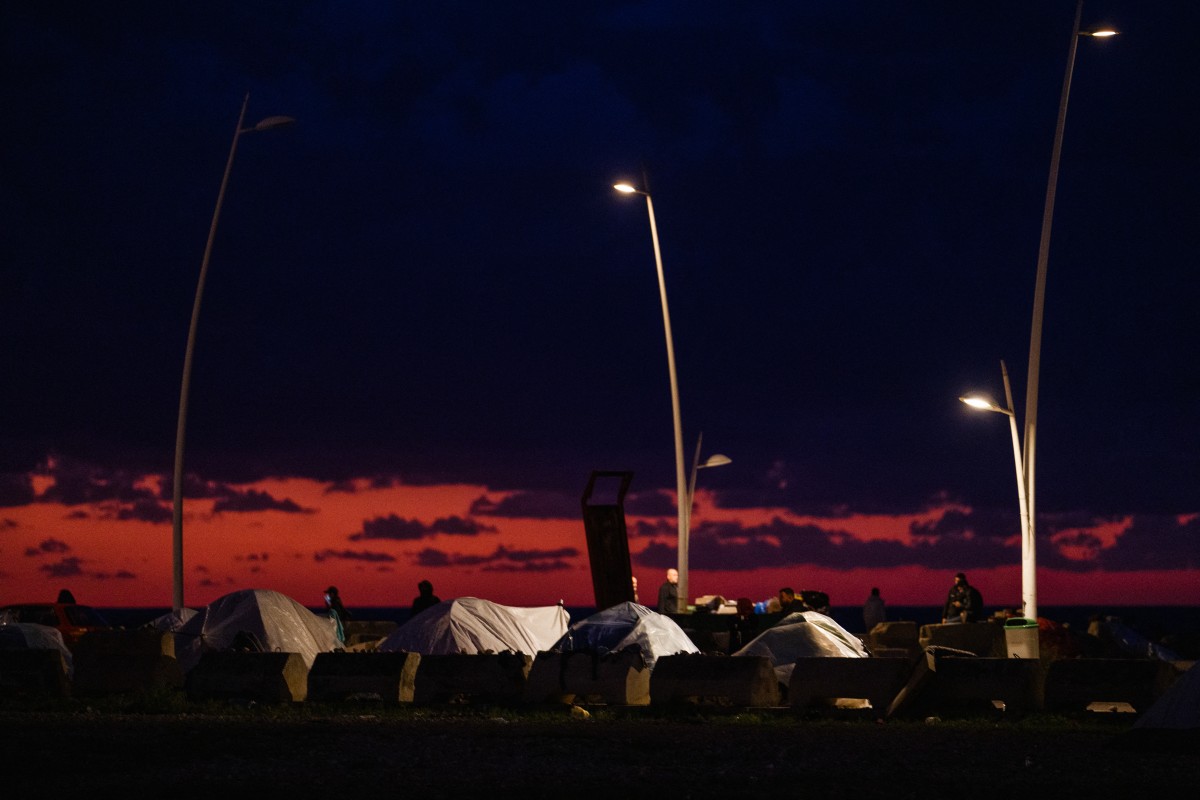 نازحون يسيرون بالقرب من خيامهم المنصوبة على طول الواجهة البحرية في بيروت (أ ف ب).