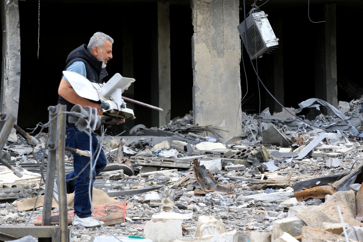 رجل يحمل آلة استخرجها من أنقاض مبنى مدمر بعد عودته إلى مدينة النبطية في جنوب لبنان (أ ف ب). 