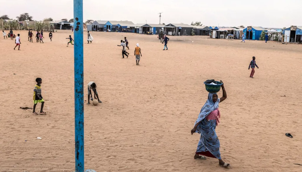 لاجئة تحمل سلة مليئة بالملابس على رأسها في مخيم مبرّة للاجئين، الذي يأوي 120 ألف لاجئ فروا من العنف وعدم الاستقرار في مالي (أ ف ب). 