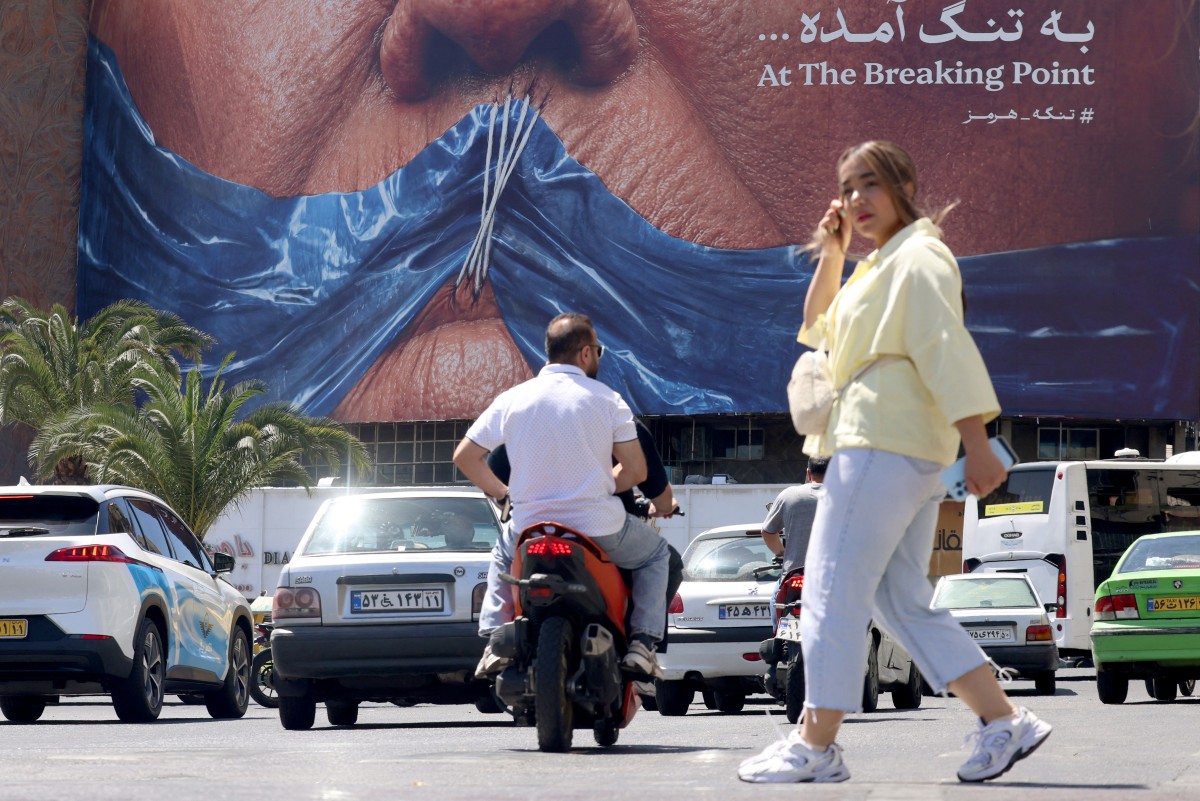 سيدة إيرانية تمر أمام لوحة دعائية مناهضة للولايات المتحدة وترامب في ساحة ولي العصر وسط طهران. (أ ف ب)