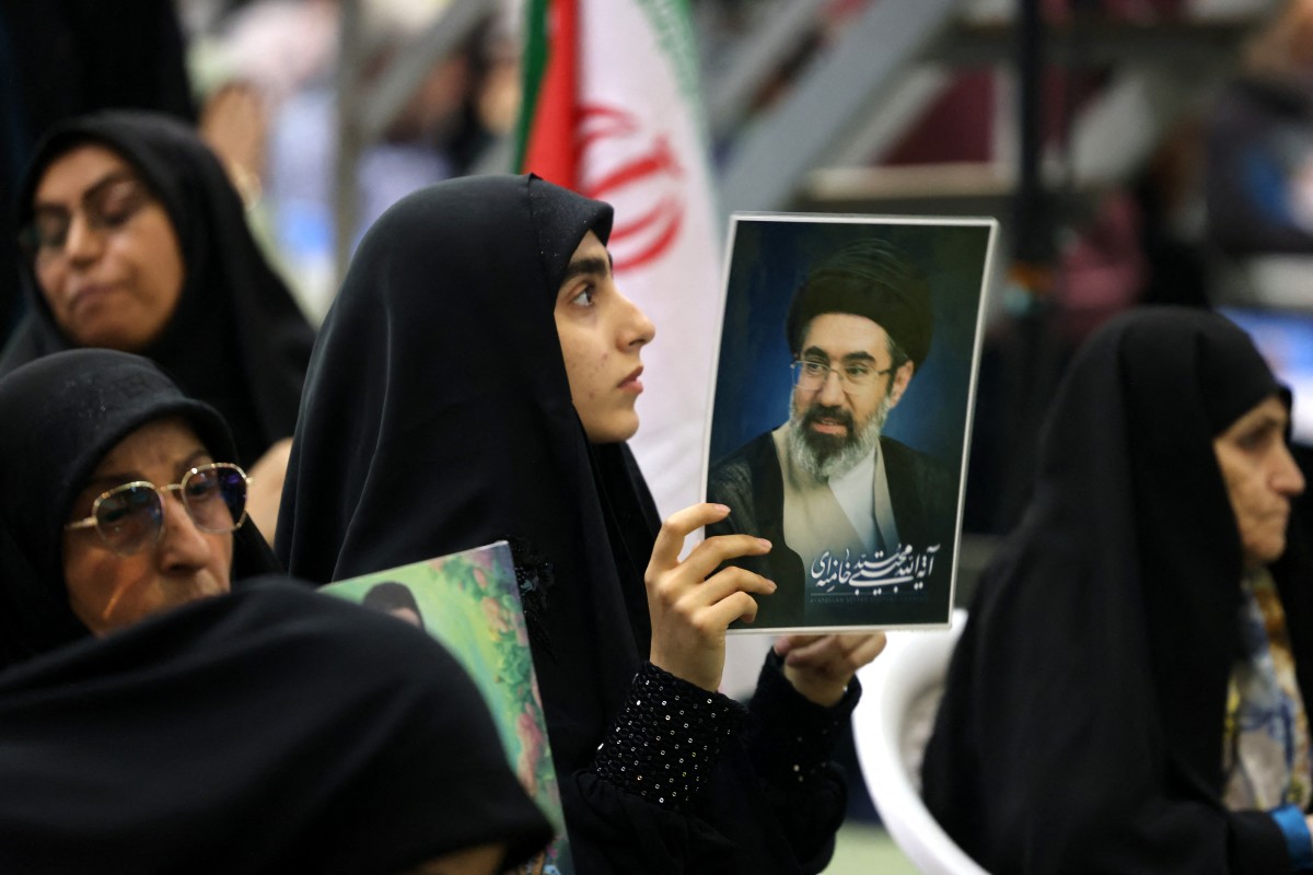 امرأة إيرانية تحمل صورة المرشد الأعلى الإيراني مجتبى خامنئي (أ ف ب). 