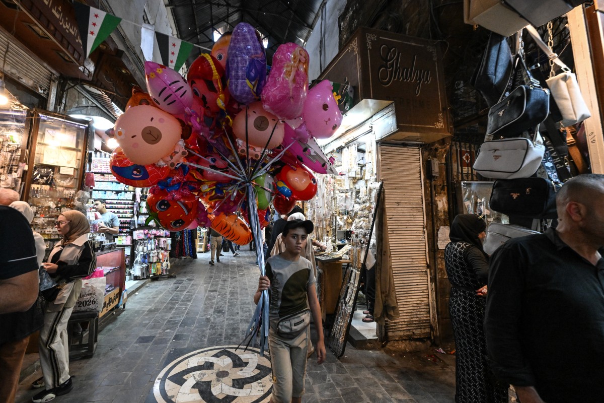 طفل يبيع بالونات في أحد أسواق دمشق. (أ ف ب)