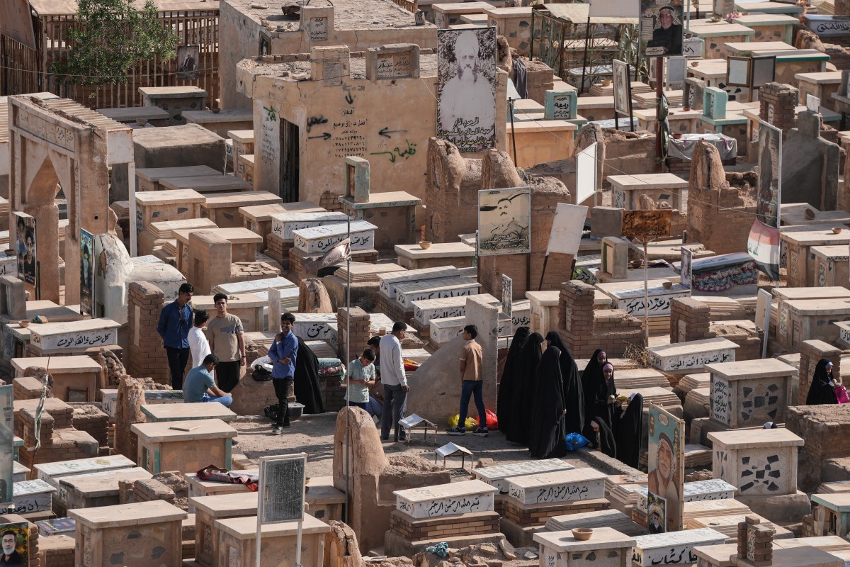  عراقيون يزورون قبور أحبائهم في اليوم الأول من عيد الأضحى في مدينة النجف المقدسة بالعراق. (أ ف ب)