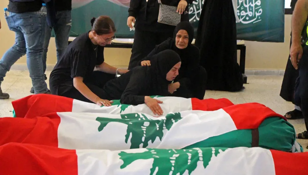 Mourners weep beside the bodies of victims of Israeli airstrikes before their funeral in Tyre (AFP)