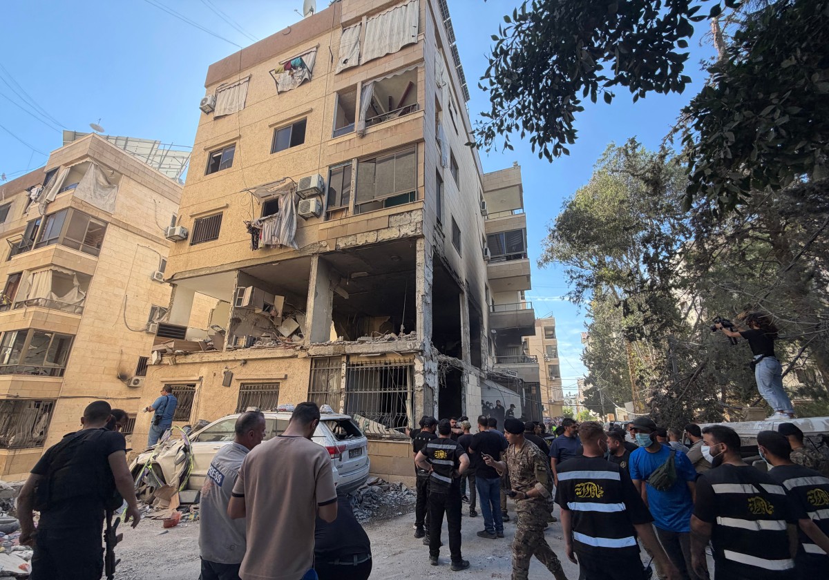 يقوم عمال الإنقاذ والسكان المحليون بتفقد الأضرار التي لحقت بمبنى إثر غارة جوية إسرائيلية في منطقة الشويفات (أ ف ب)