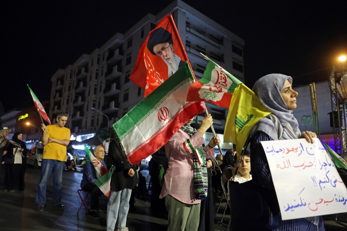 إيرانية تحمل علم حزب الله خلال تجمع ليلي داعم للنظام،  في طهران. (أ ف ب)