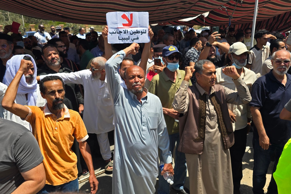 متظاهرون ليبيون أمام مقر المفوضية السامية لشؤون اللاجئين في طرابلس، خلال تحرك طالب بإغلاق مكاتب المفوضية ورفض توطين الأجانب. (أ ف ب)