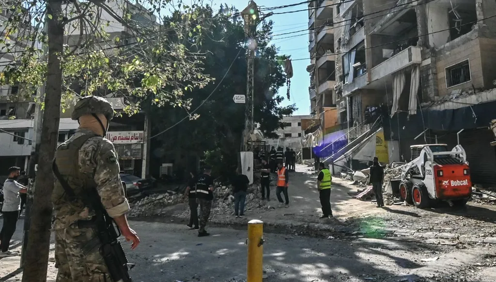 جندي لبناني يقف حراسة بينما تعمل فرق الطوارئ في موقع غارة جوية إسرائيلية استهدفت مبنى سكني بضواحي بيروت الجنوبية (أ ف ب)