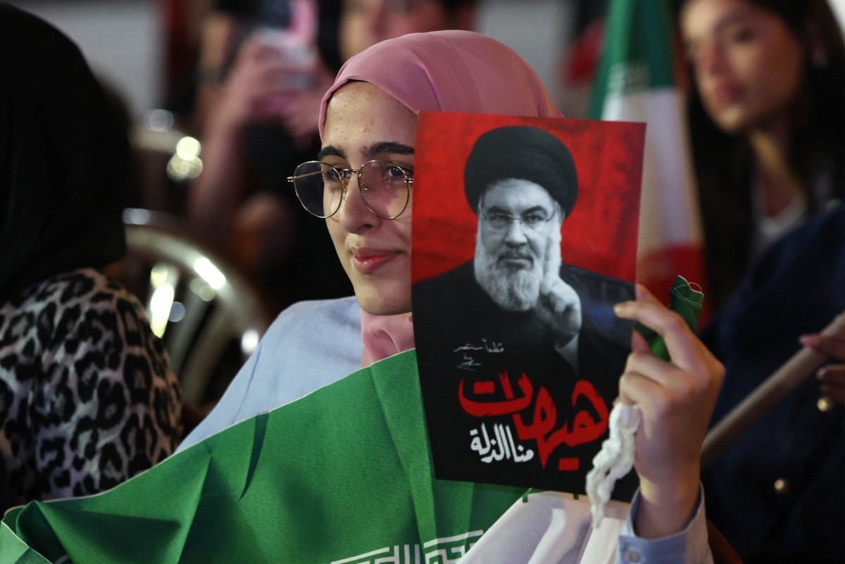 فتاة تحمل صورة الأمين العام السابق لحزب الله السيد حسن نصرالله خلال تظاهرة مناهضة للولايات المتحدة وإسرائيل في الضاحية الجنوبية لبيروت، 10 حزيران/يونيو 2026. (أ ف ب)