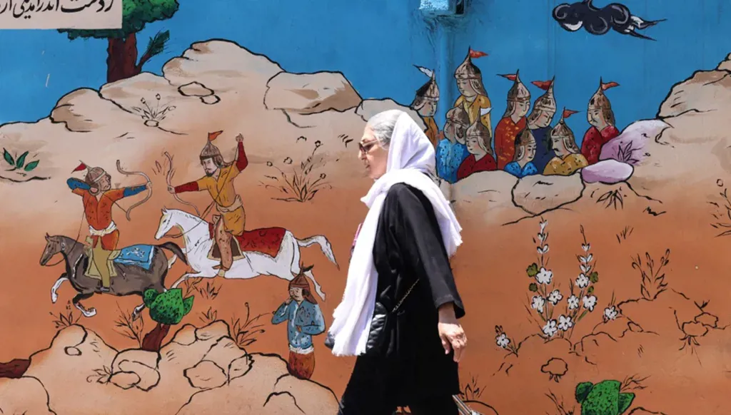 سيدة إيرانية تمر أمام جدارية مستوحاة من مشاهد تاريخية وأدبية في طهران، 15 حزيران/يونيو 2026. (أ ف ب)