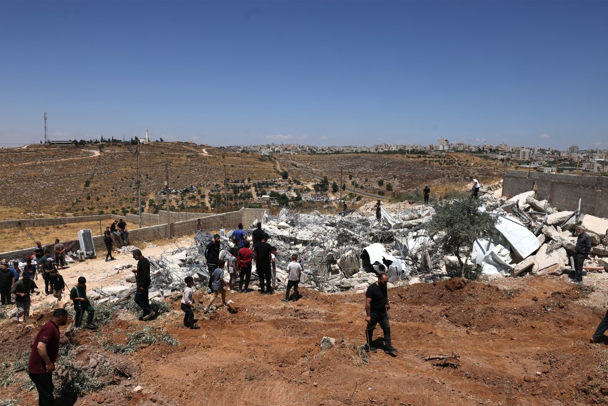 فلسطيني يركل قنبلة غاز مسيل للدموع أطلقتها قوات الأمن الإسرائيلية، جنوب مدينة الخليل في الضفة الغربية المحتلة (أ ف ب)