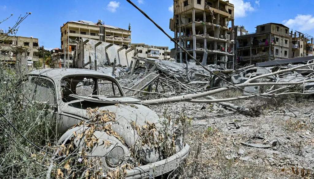 صورة لمركبة مدمرة ومبانٍ في بلدة النبطية الفوقا في جنوب لبنان (أ ف ب)