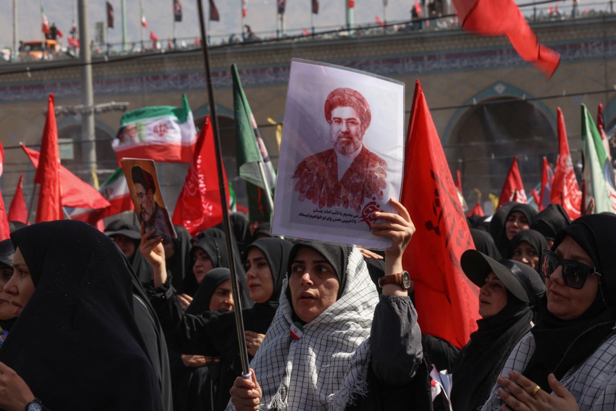 سيدة ترفع صورة المرشد الأعلى مجتبى خامنئي خلال مراسم تشييع والده في طهران. (أ ف ب)