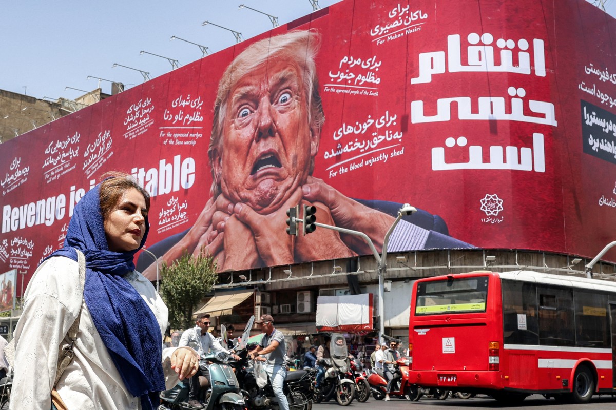 سيدة تمر أمام لوحة إعلانية في وسط طهران تتوعد بالانتقام من الرئيس الأميركي دونالد ترامب. (أ ف ب)