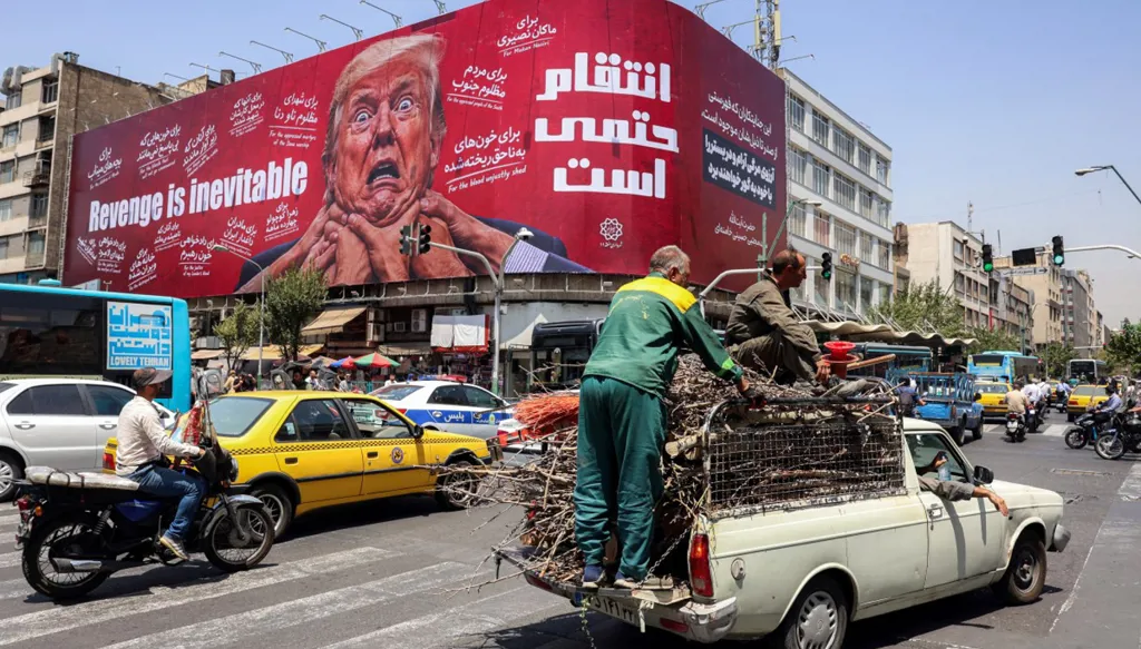 يمرّ سائقون قرب لوحة إعلانية كبيرة تتوعد بالانتقام من الرئيس الأميركي دونالد ترامب، في وسط طهران (أ ف ب)