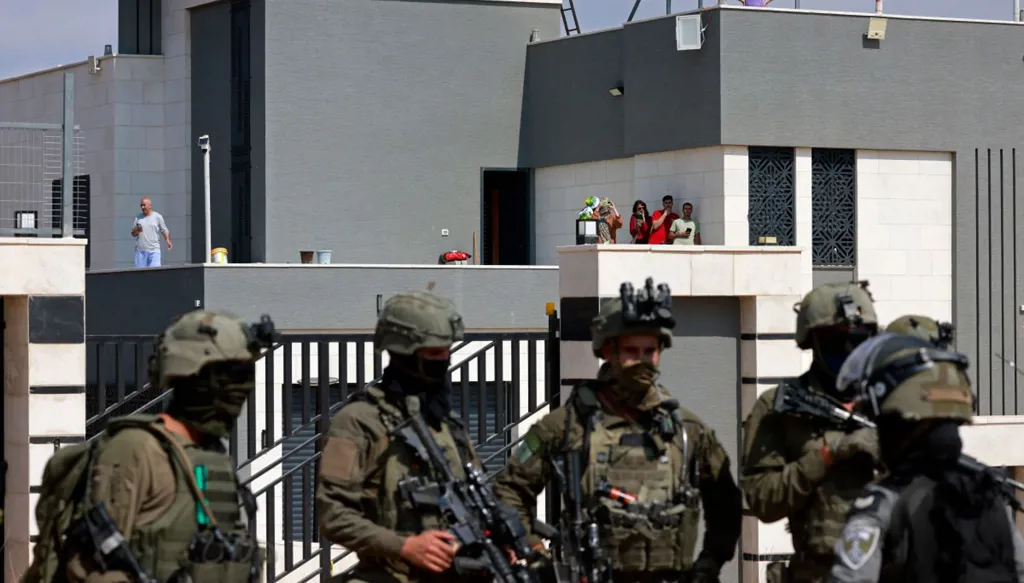 جنود إسرائيليون أمام مدخل منزل فلسطيني يحاصره مستوطنون في بلدة قصرة، جنوب نابلس، في 14 آب/أغسطس 2026. (النهار)