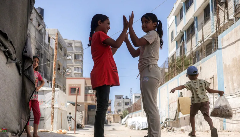 فتاتان تلعبان قرب مبنى مدرسة في خان يونس جنوب قطاع غزة في 25 آب/أغسطس 2026. (أ ف ب)