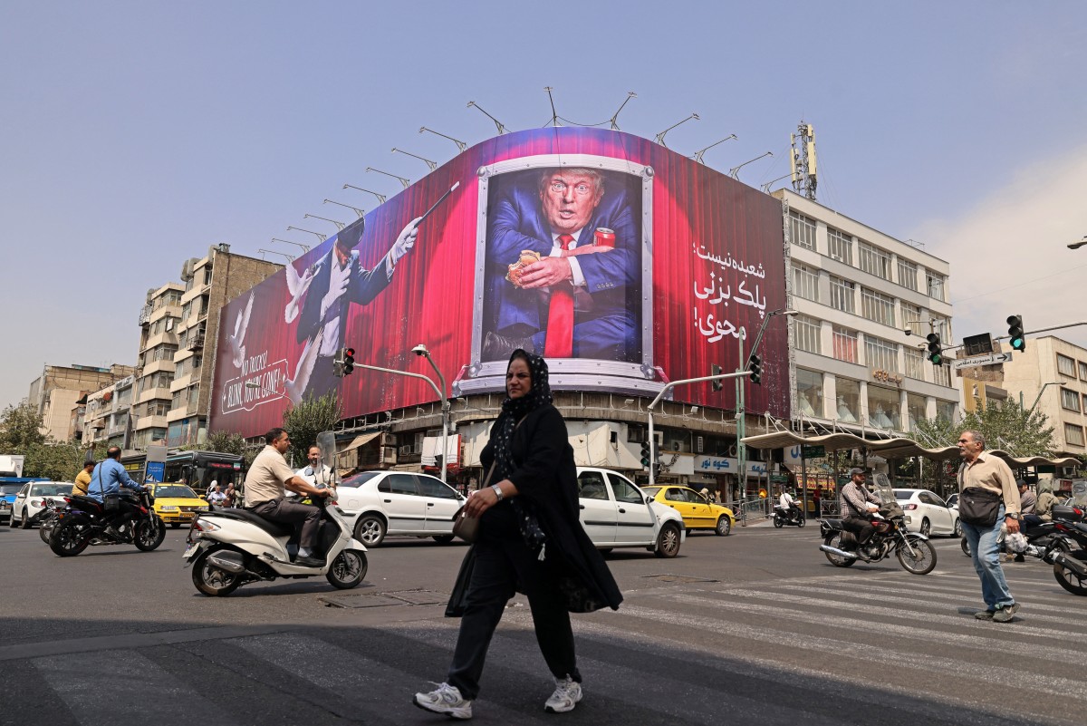 سيدة تمر أمام لوحة إعلانية تُظهر الرئيس الأميركي دونالد ترامب داخل حاوية طعام، في وسط طهران، 31 آب/أغسطس 2026. (أ ف ب)