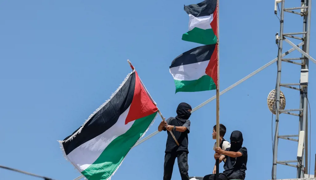 فتية يلوحون بالأعلام الفلسطينية (أ ف ب)   
