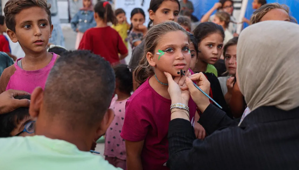 طفلة فلسطينية تُرسم على وجهها خلال عرض كرتوني للأطفال في مخيم للنازحين بمدينة غزة، 5 أيلول/سبتمبر 2026. (أ ف ب)