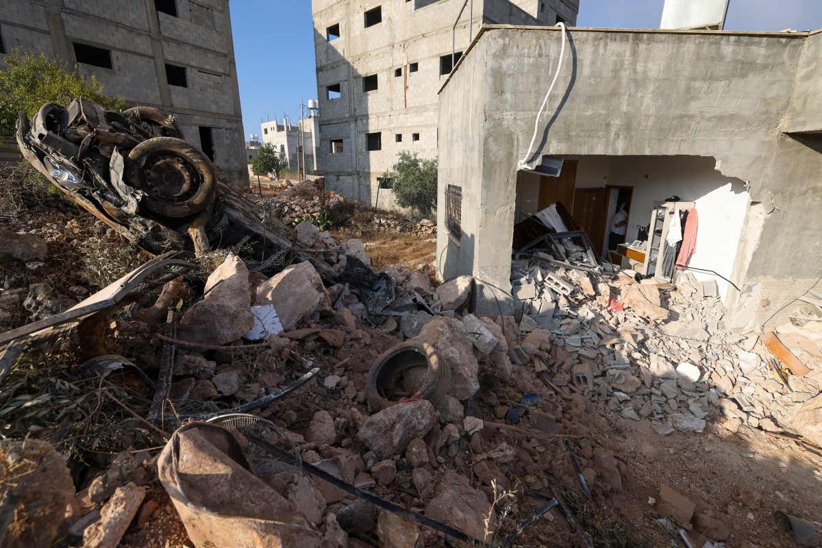 فلسطينيون يتفقدون منزلاً عائلياً دمره الجيش الإسرائيلي في الضفة الغربية، (أ ف ب).