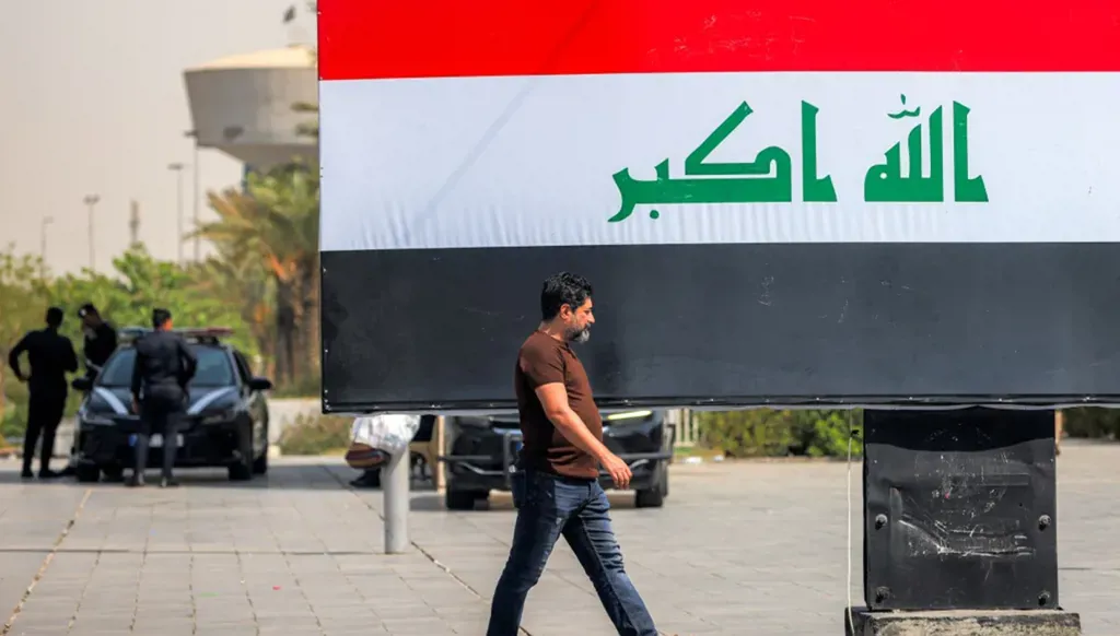 رجل يمر أمام لوحة إعلانية تحمل العلم العراقي في ساحة التحرير وسط بغداد، 22 أيلول/سبتمبر 2026. (أ ف ب)