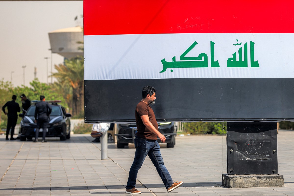 رجل يمر أمام لوحة تحمل العلم العراقي في ساحة التحرير وسط بغداد، في 22 أيلول/سبتمبر 2026. (أ ف ب)
