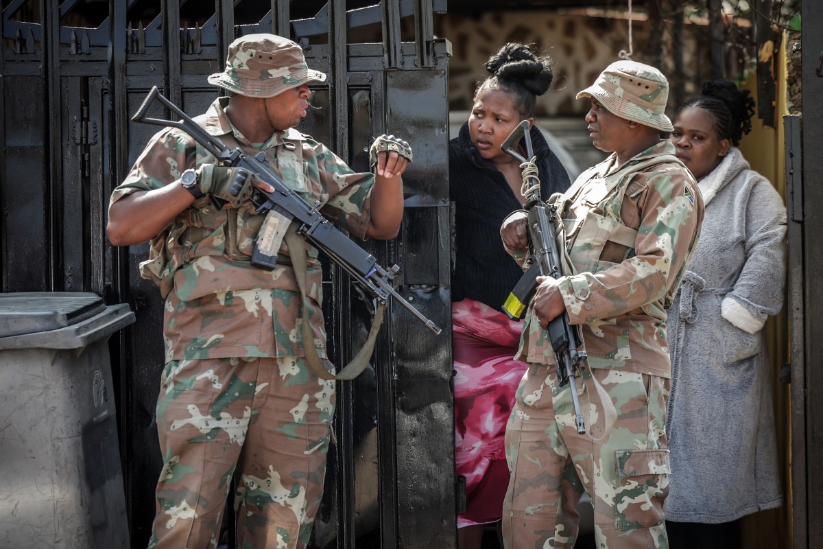 يتحدث أفراد من قوة الدفاع الوطني الجنوب أفريقية (SANDF) مع سكان بالقرب من موقع اقتحام مسلحين يحملون بنادق هجومية لحانة في جوهانسبرغ في 27 أيلول/سبتمبر 2026. (أ.لإ.ب.)
