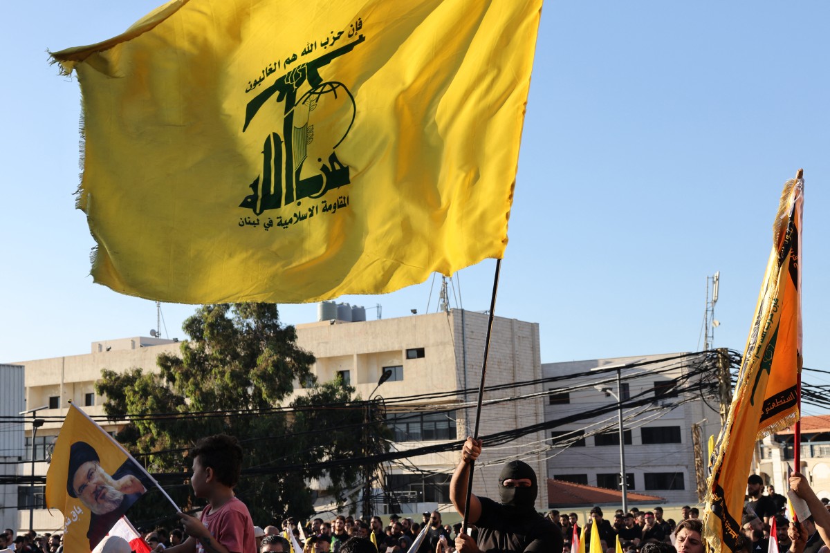 رفع علم حزب الله خلال احتفال بالذكرى السنوية الثانية لاغتيال نصرالله (أ ف ب).