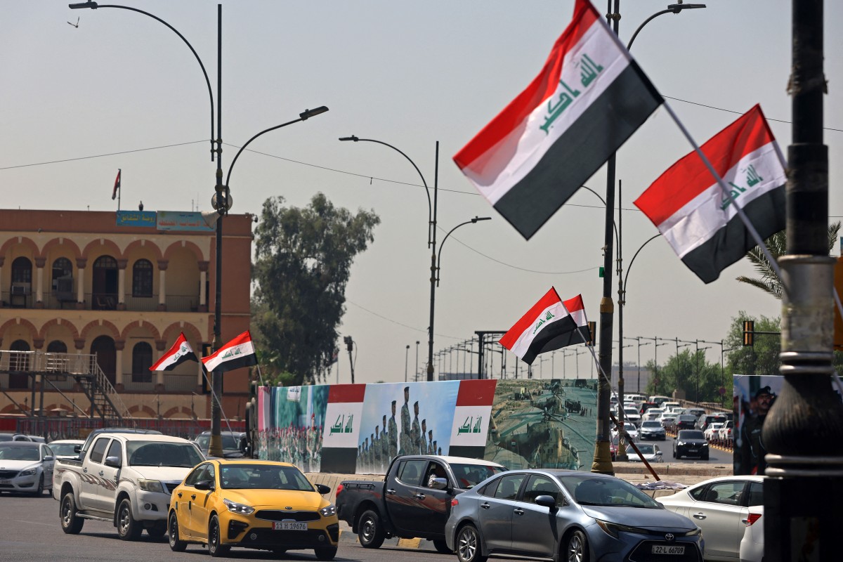 مركبات تمر أمام أعلام عراقية منتشرة على طول أحد الشوارع في ميدان التحرير في بغداد. (ا ف ب)