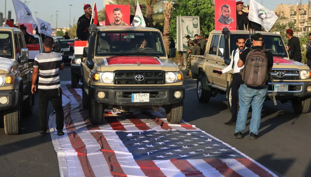 قوات الحشد الشعبي في العراب تسير على علم أميركي بظل تصعيد في الشرق الأوسط. (أ ف ب)