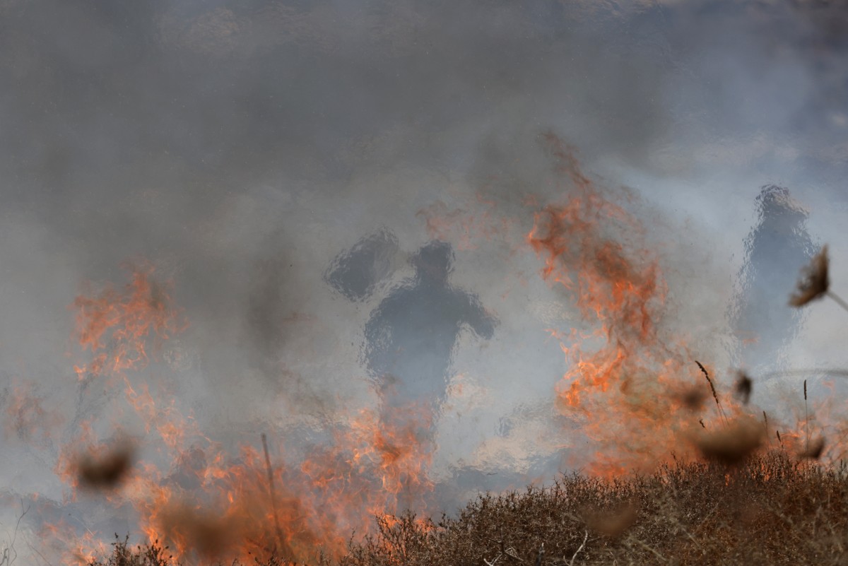 يحاول مزارعون فلسطينيون محليون إخماد حرائق اندلعت في أراضيهم بعدما أطلق جنود من الجيش الإسرائيلي الغاز المسيل للدموع عليهم أثناء قطفهم الزيتون (أ ف ب)