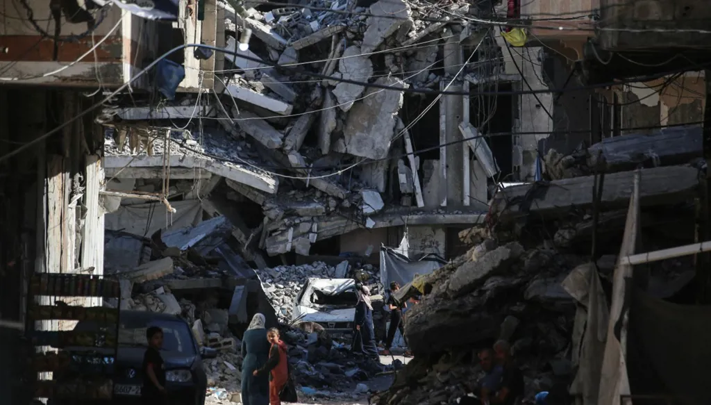 فلسطينيون يسيرون في شارع تحيط به مبانٍ مدمّرة في مخيم جباليا للاجئين شمالي قطاع غزة (أ ف ب).