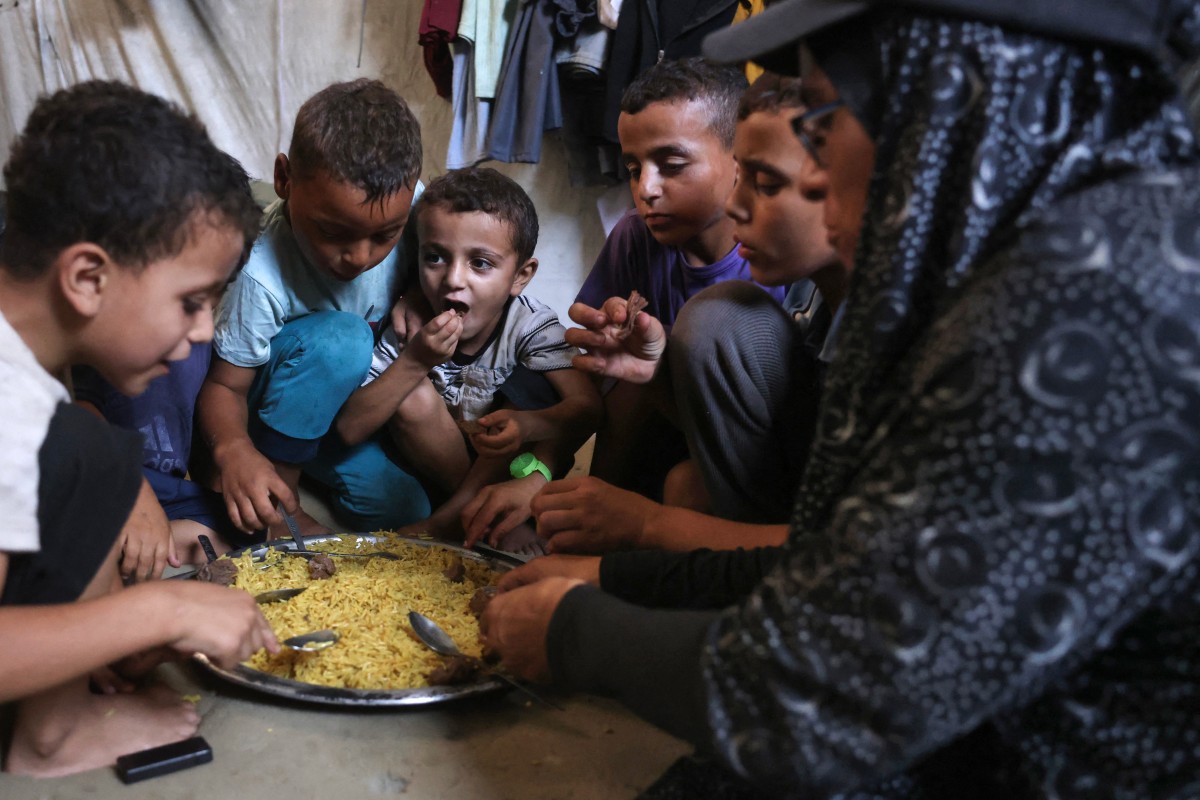 امرأة فلسطينية تتناول وجبة مع أطفالها في خان يونس جنوبي قطاع غزة. (أ ف ب)