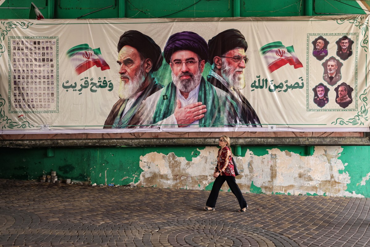 مواطن ايراني يعبر بجوار جدارية في طهران (أ ف ب)