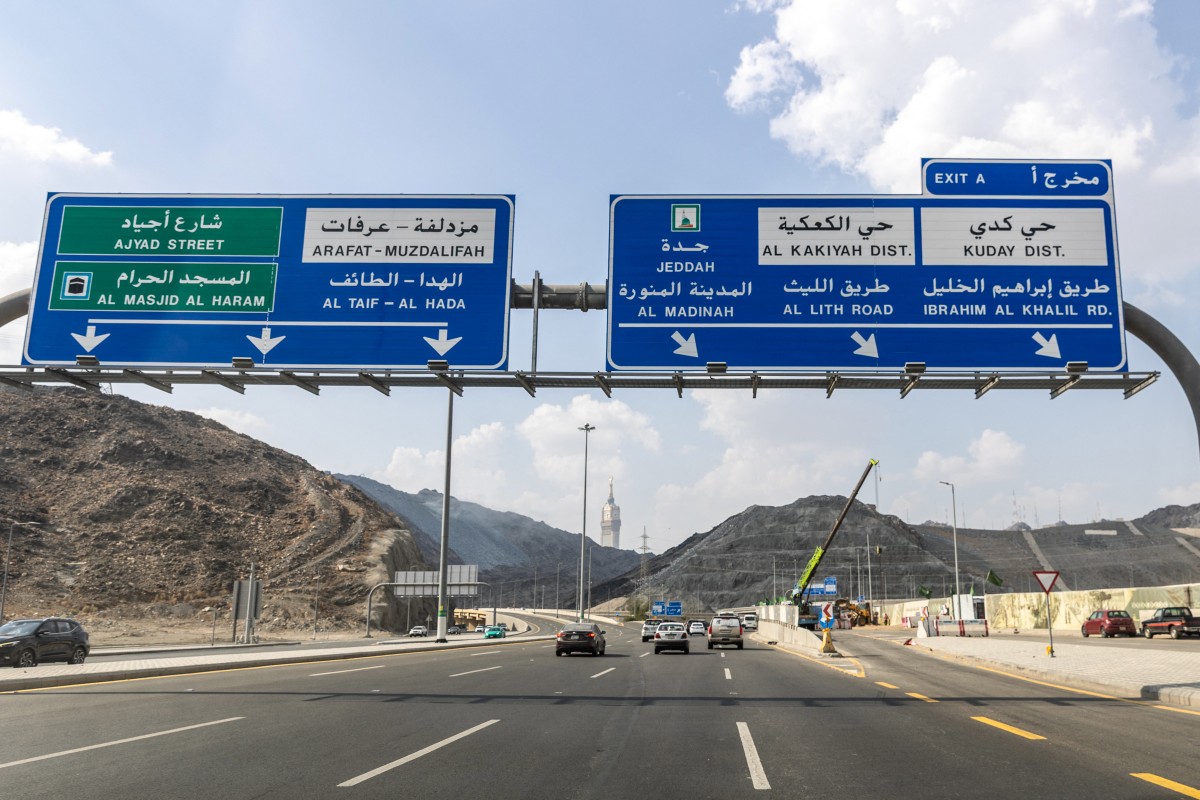 سيارات تسير على طول طريق تحت لافتات إرشادية في مكة المكرمة. (أ ف ب)