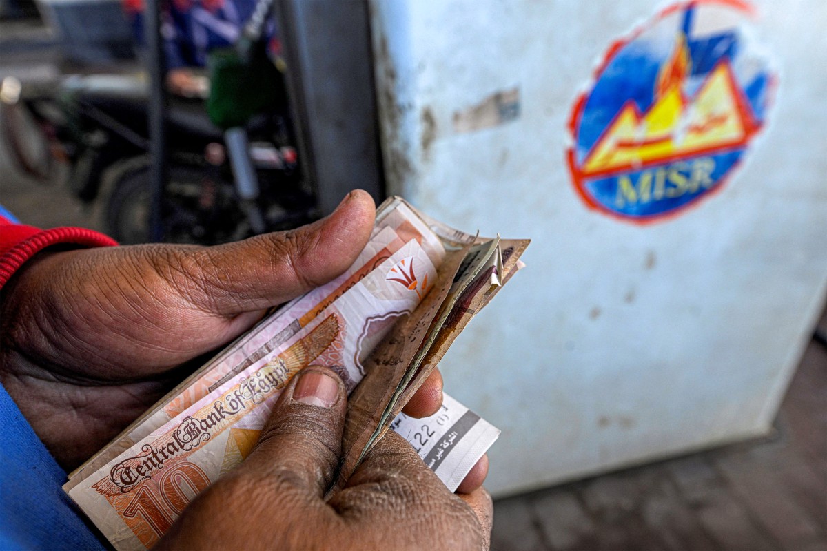 عامل مصري يعد الأوراق النقدية بعد ملء خزان سيارة في محطة وقود بالجيزة في 10 آذار/مارس 2026 (أ ف ب)