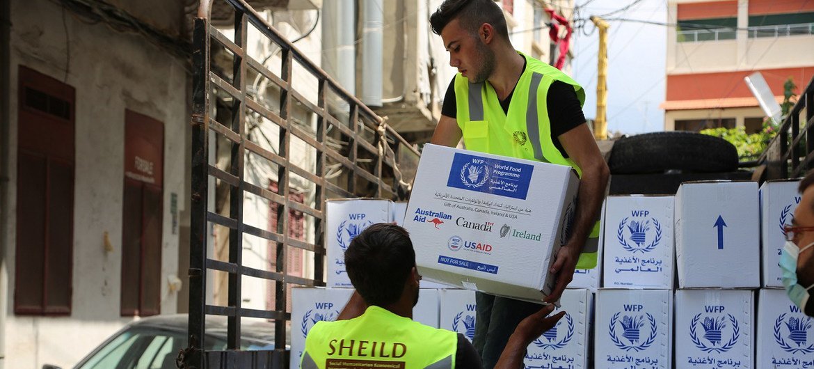 عمال يفرغون حمولة المعونات الغذائية التي أرسلها برنامج الأغذية العالمي في مركز كاراجوسيان في بيروت (الأمم المتحدة)