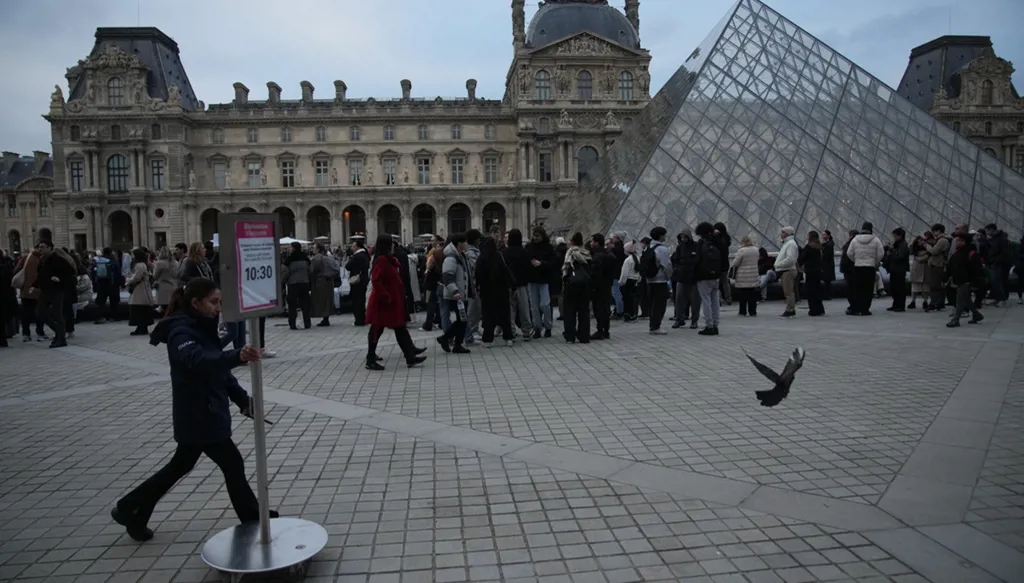 People wait at the entrance of the Louvre museum as employees were set to vote on whether to extend a strike that shut the world's most visited museum, as unions protest chronic understaffing, building deterioration and recent management decisions Wednesday, Dec. 17, 2025 in Paris. (AP Photo/Christophe Ena)