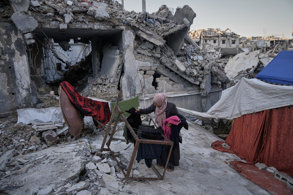Saadia Abu Duheir, a mother of six, hangs laundry beside a tent set up over the rubble of her family's collapsed home in the Sheikh Radwan neighborhood of Gaza City, Wednesday, Nov. 26, 2025. (AP Photo/Jehad Alshrafi)